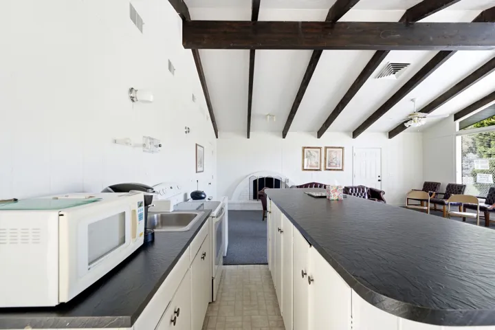 Kitchenette with white cabinetry and dark countertops