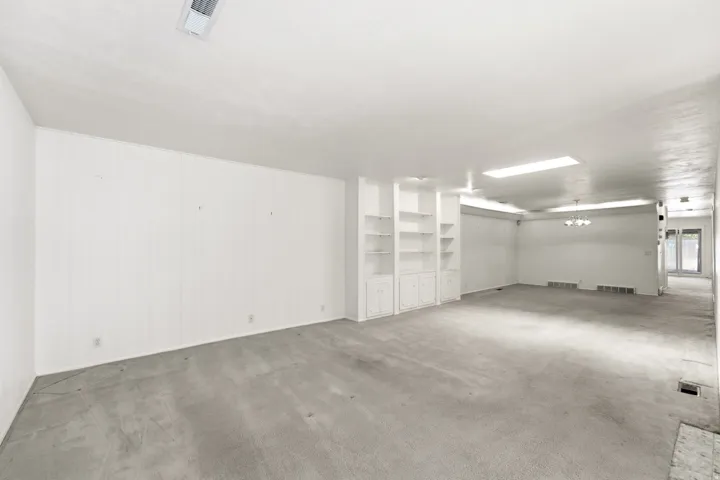 Expansive room featuring built-in shelving, recessed lighting, wall paneling, and carpeting