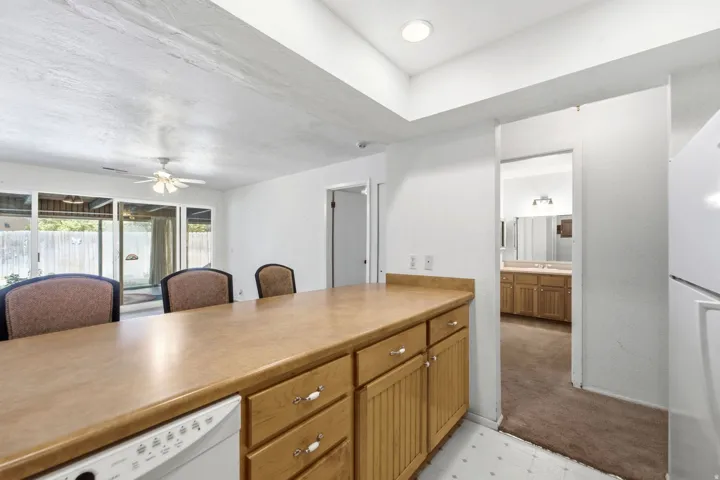 Kitchen bar seating with wood cabinetry and an integrated dishwasher