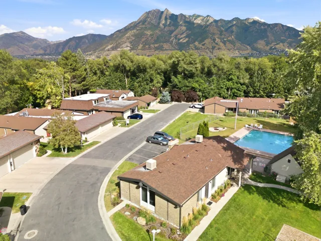 Community with a swimming pool, mature trees, and a mountain backdrop