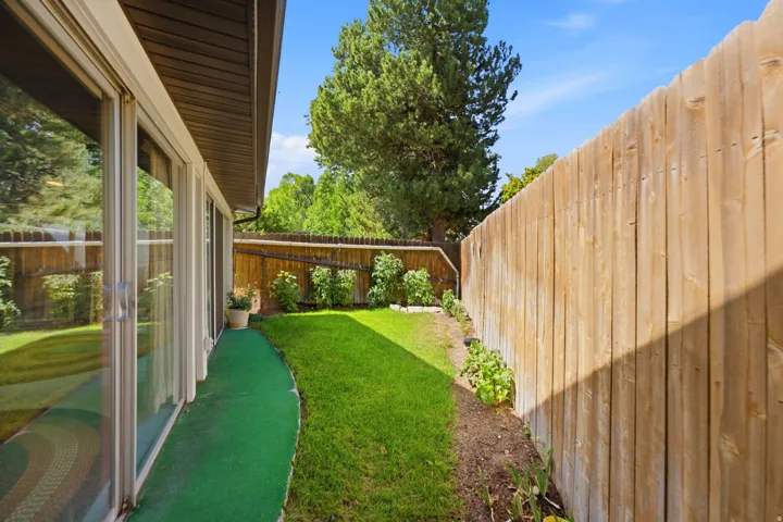 Expansive private yard featuring a wood fence, mature landscaping, and sliding glass doors