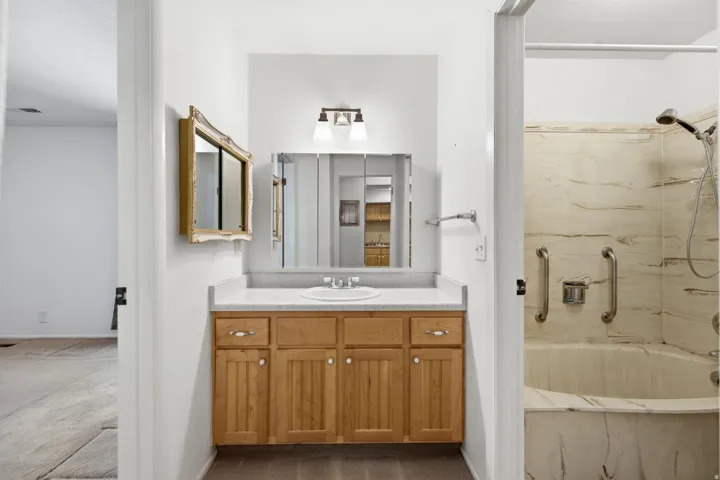 Single vanity with light wood-finish cabinetry, white countertop, and integrated sink
