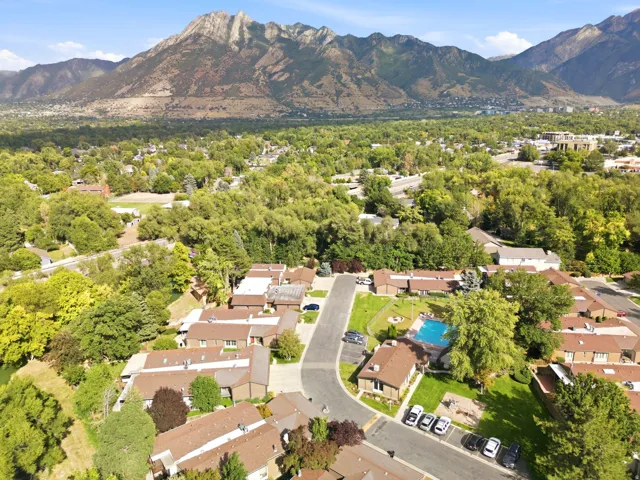 Mountain backdrop with extensive green landscaping, residential community, and a central swimming pool