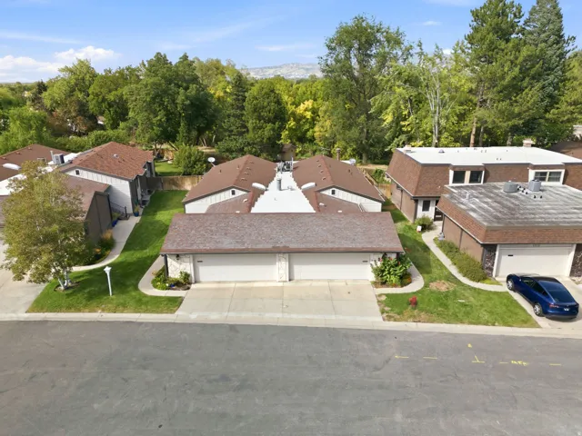 Residential cluster featuring attached garages and individual walkways, surrounded by mature trees and landscaping