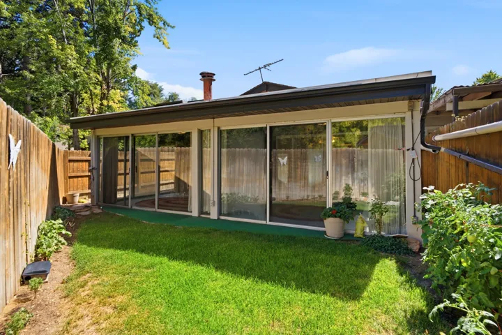 Expansive backyard featuring a manicured lawn, established perimeter fencing, and a sunroom with sliding glass doors