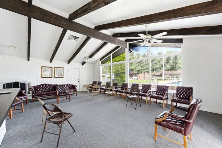 Vaulted ceilings with exposed beams, large picture windows, white paneled walls, and a built-in fireplace