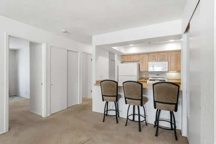 Kitchen featuring wood-finish cabinetry, white appliances, and a tiled backsplash