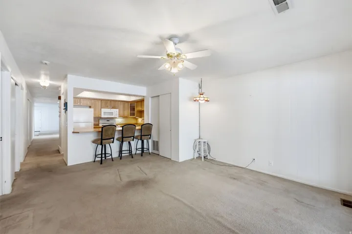 Kitchen pass-through with breakfast bar, wood-finish cabinetry, and white appliances