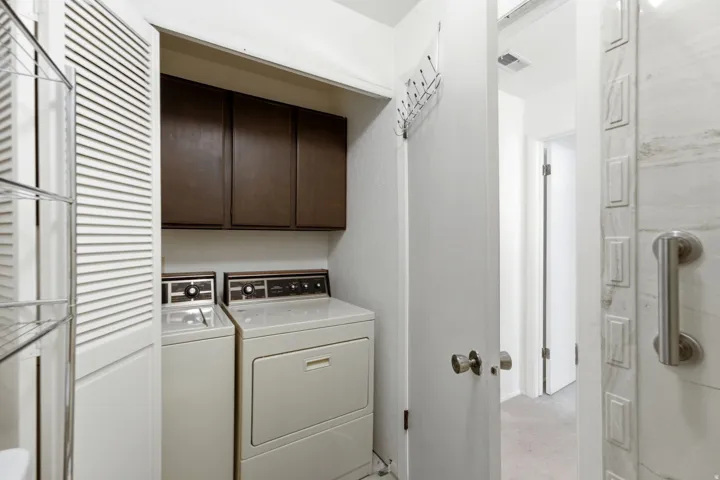 Dedicated laundry area with upper cabinetry and louvered bifold doors