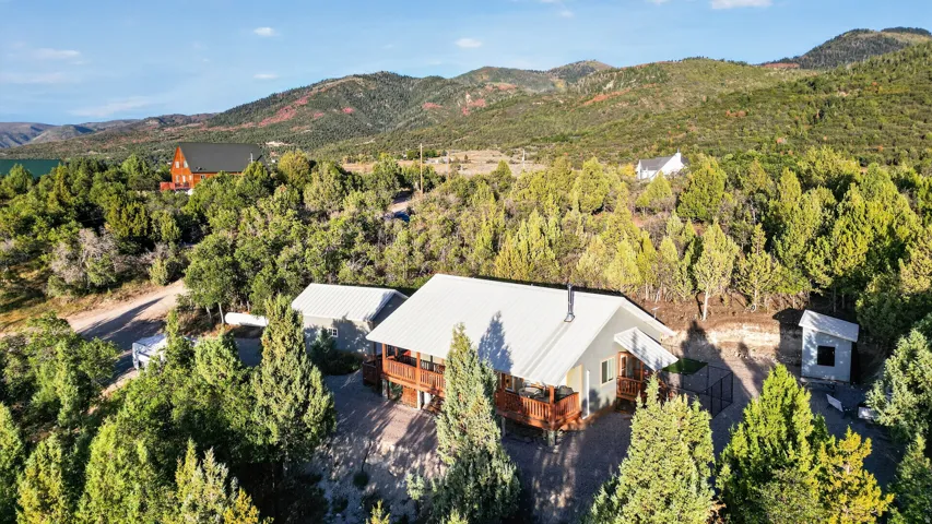 Property features a light-colored metal roof, expansive wood deck, and a detached structure