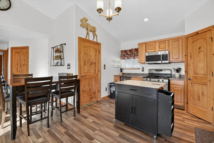 Kitchen featuring wood-finish flooring, natural wood cabinetry, stainless steel appliances, and a mobile kitchen island with a wood-tone top