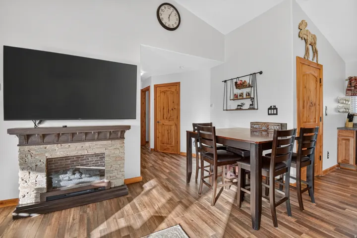 Stone-clad fireplace with a wood mantel, wood-finish flooring, and natural wood doors