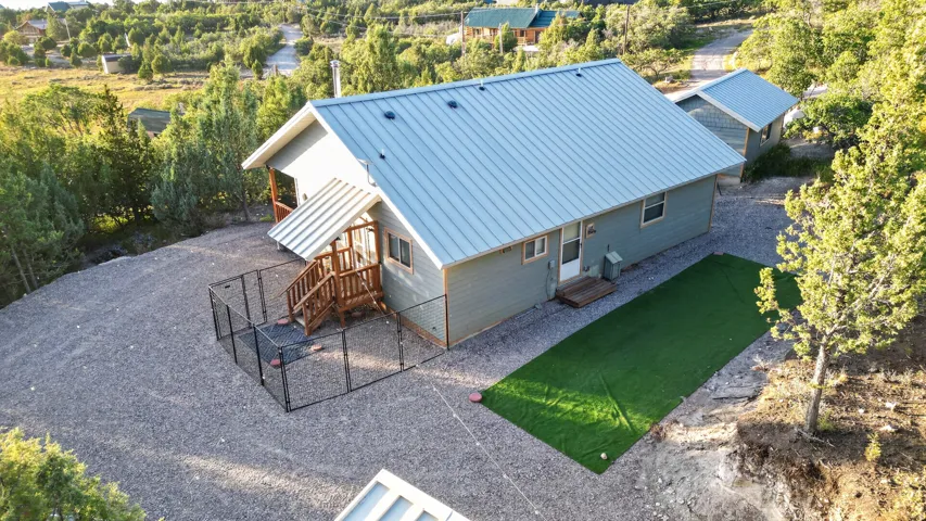 Property featuring a light blue metal roof, gravel ground cover, and a fenced patio area