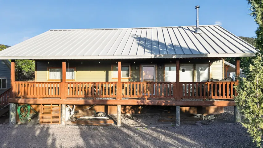 Covered front porch with wood railings and posts, metal roof, and light-colored siding