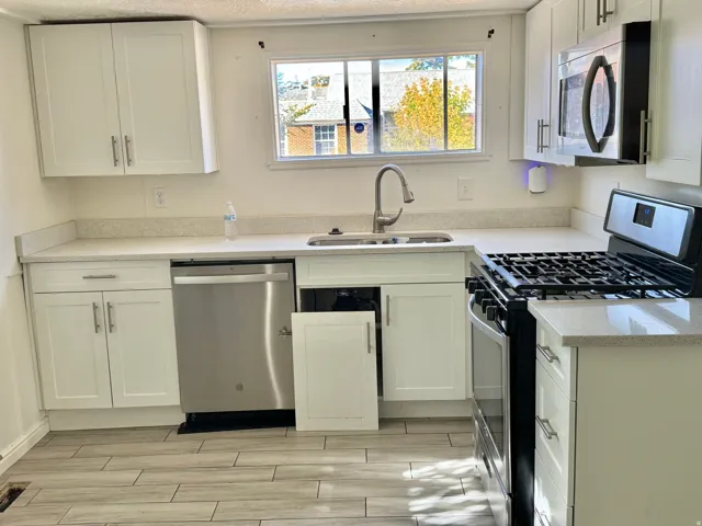White shaker cabinetry, light-toned countertops, stainless steel appliances, and wood-finish flooring
