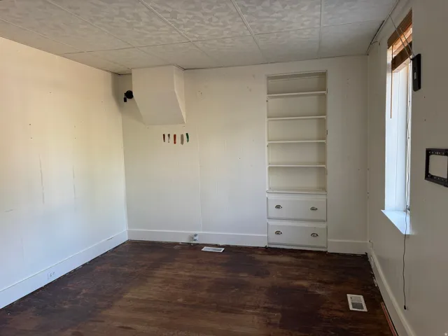 Built-in shelving with integrated drawers, wood-finish flooring, and natural light from a single window
