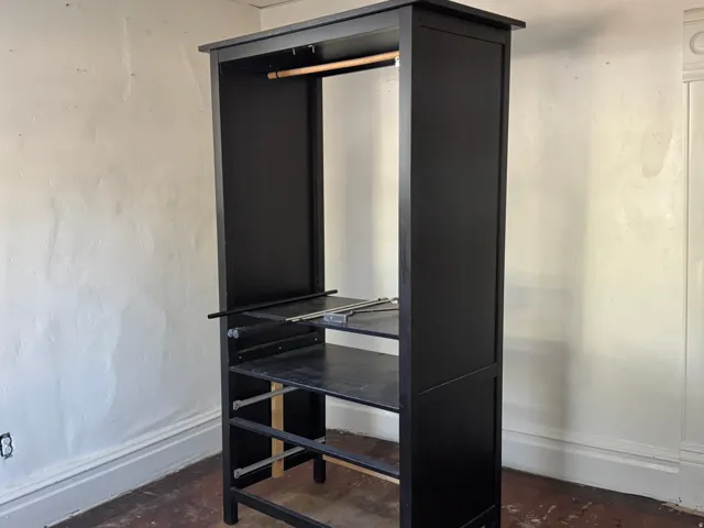 Black storage unit featuring an upper hanging rod and multiple open shelves