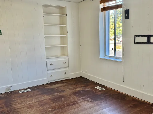Built-in shelving unit with lower drawers, sash window, and panel-style wall finishes