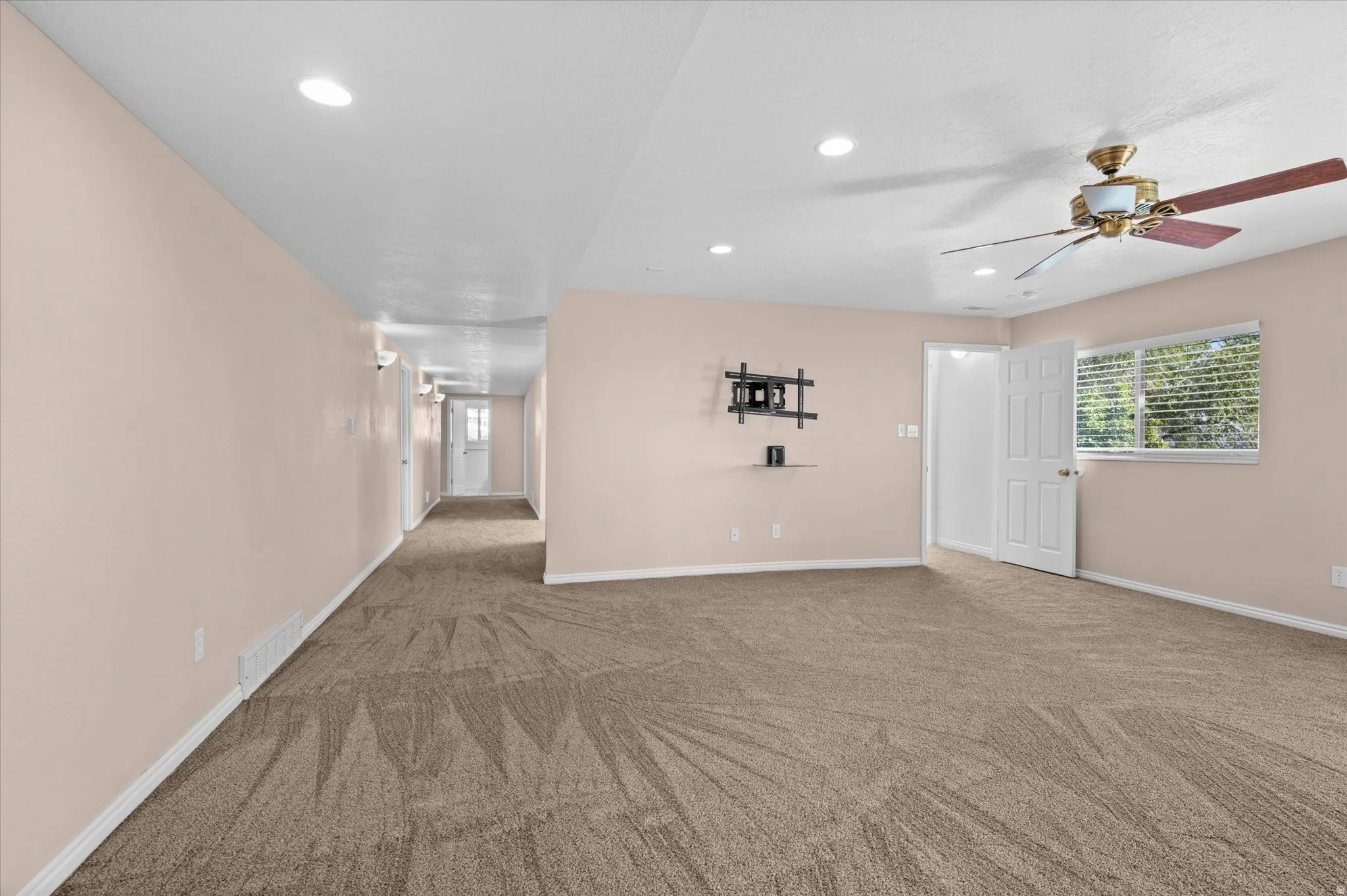 Basement Family Room w/gas fireplace, custom bookshelf and cabinets, and exit to backyard/deck. Hallway to bonus room and bedrooms.