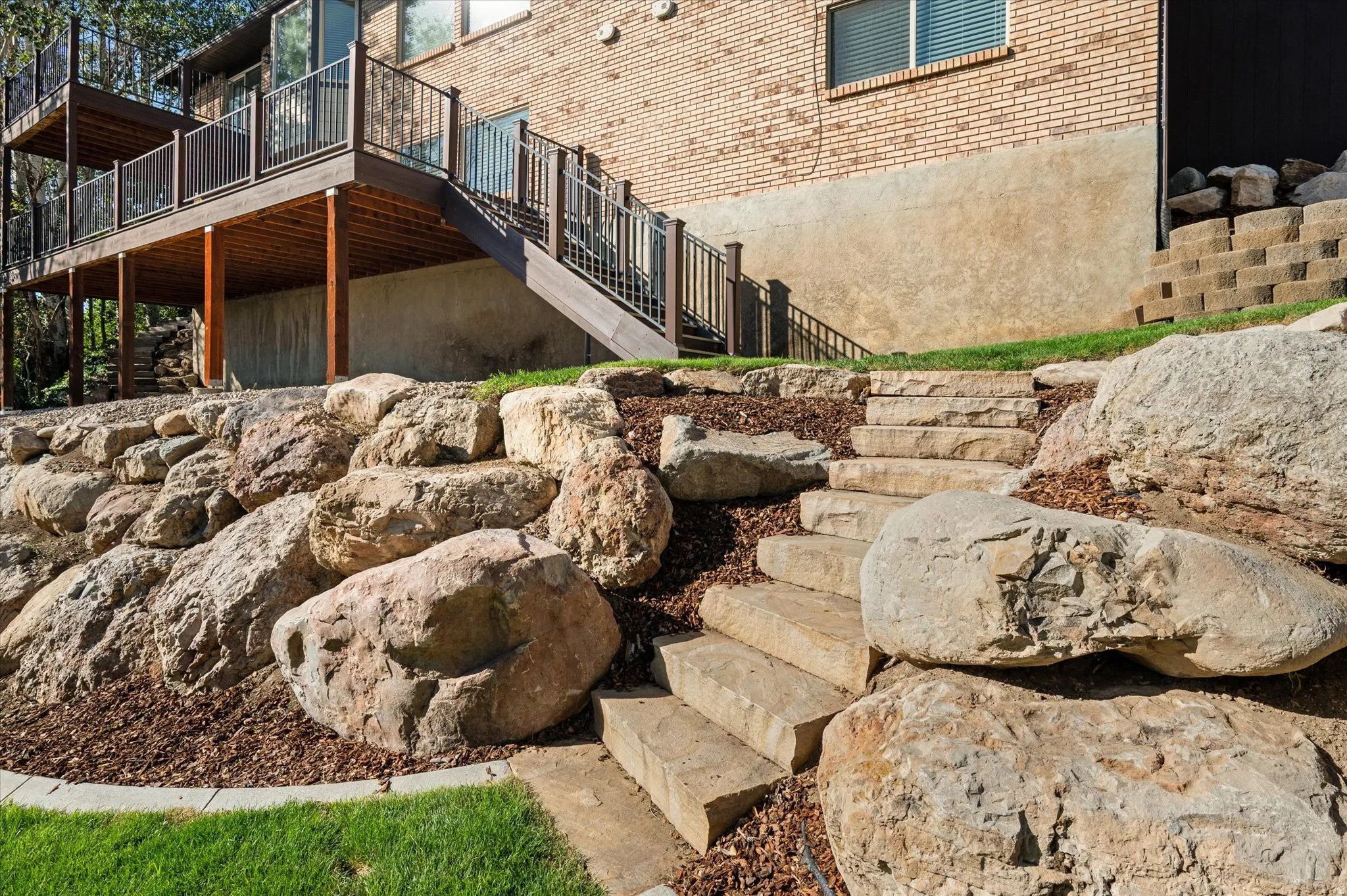 Stone steps from deck entrance to large manicured yard for fun!