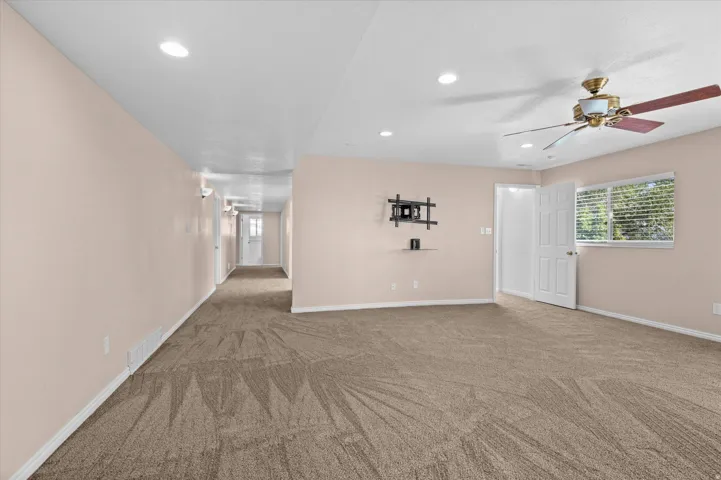Basement Family Room w/gas fireplace, custom bookshelf and cabinets, and exit to backyard/deck. Hallway to bonus room and bedrooms.