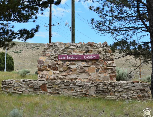 Stone monument with a "Lake Rockport Estates" sign, set against a backdrop of natural terrain