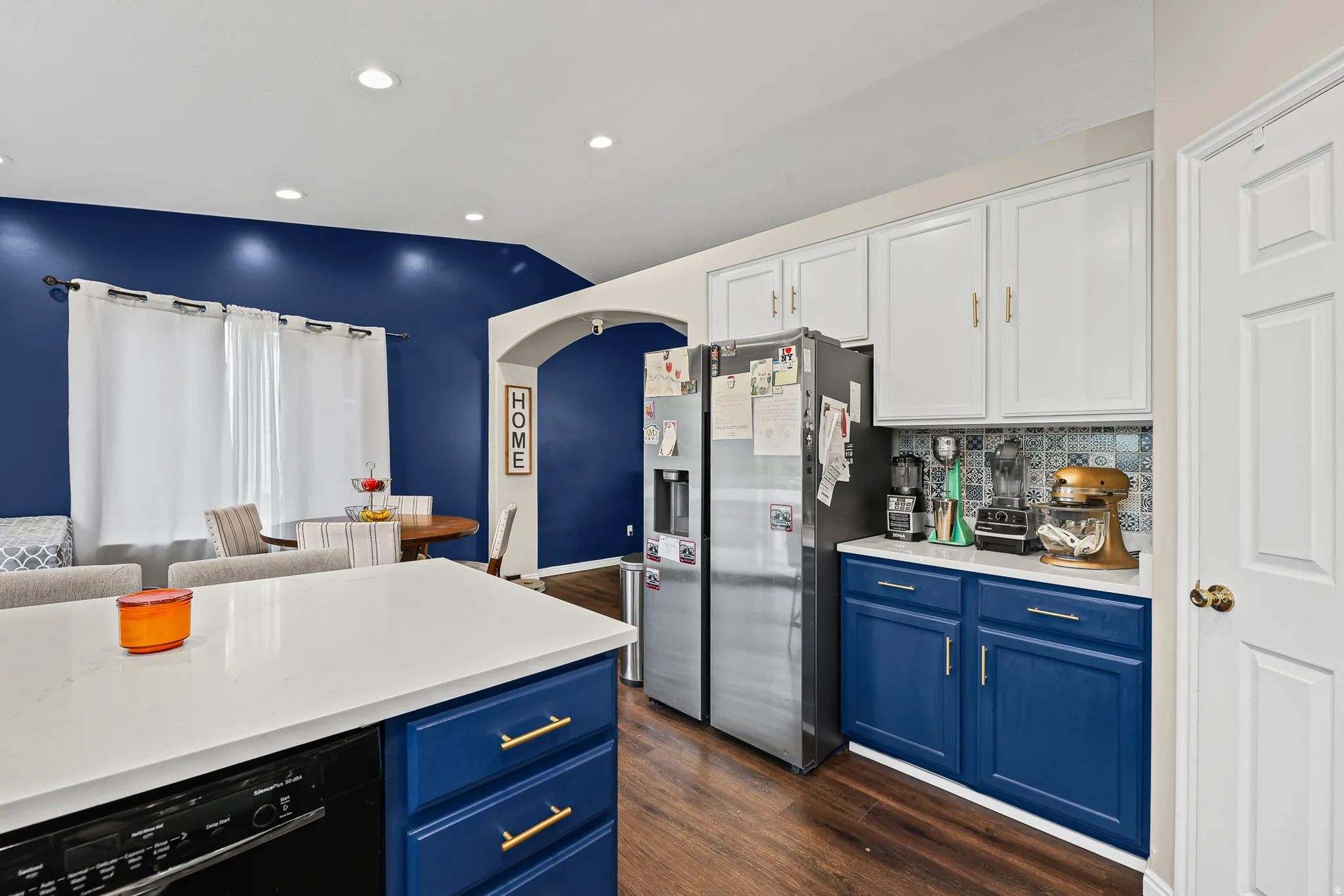 Kitchen featuring a stainless steel refrigerator, white cabinetry, blue lower cabinets, and a patterned tile backsplash