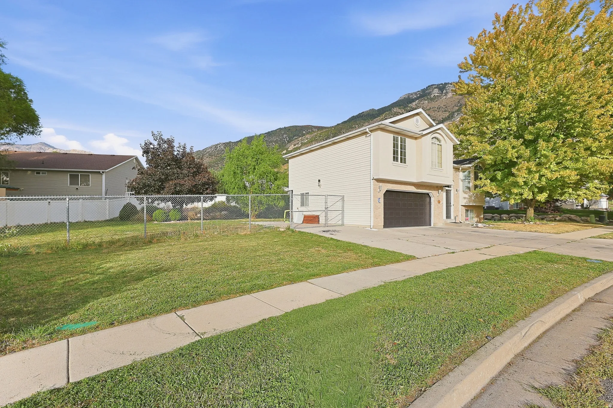 Two-story residence with light-colored siding, a prominent two-car garage, and a paved driveway