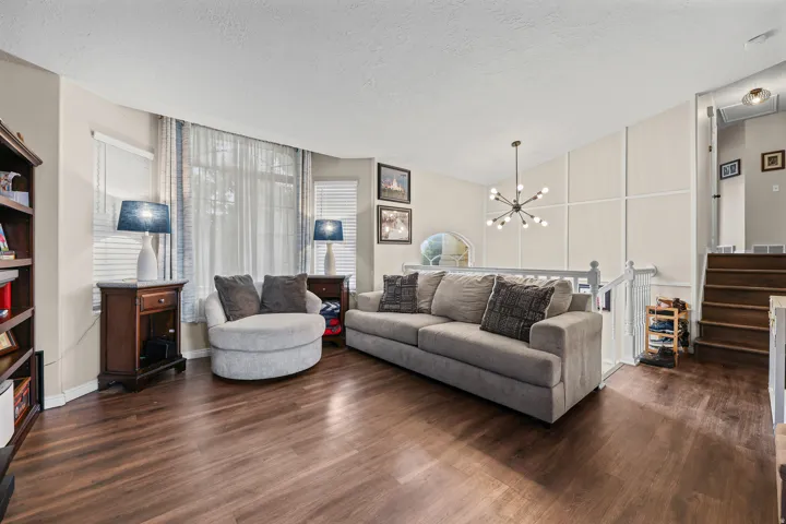Wood-finish flooring, bay window, built-in shelving, contemporary chandelier, and panel molding accent wall