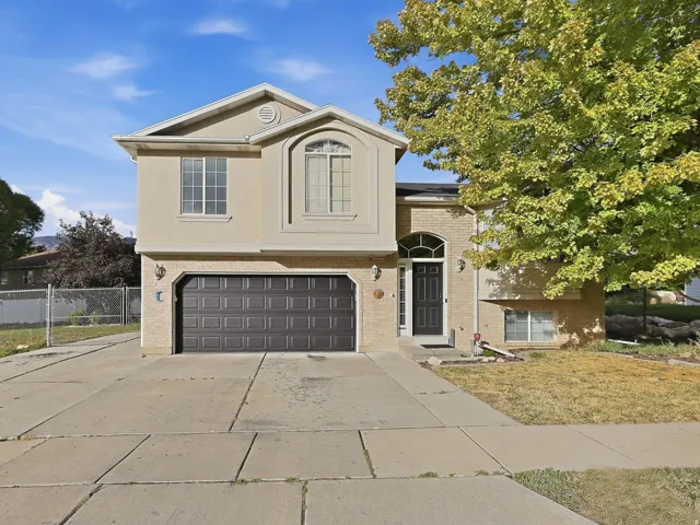 Stucco and brick exterior with an arched entry, a two-car garage, and a concrete driveway
