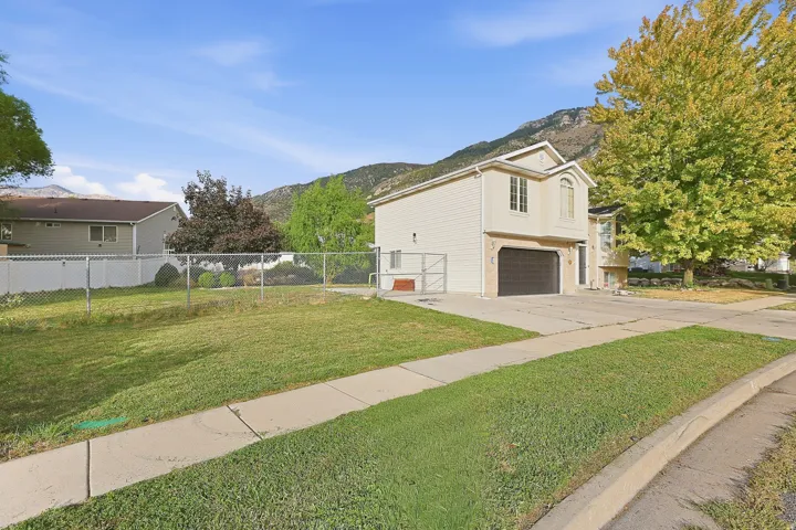 Two-story residence with light-colored siding, a prominent two-car garage, and a paved driveway