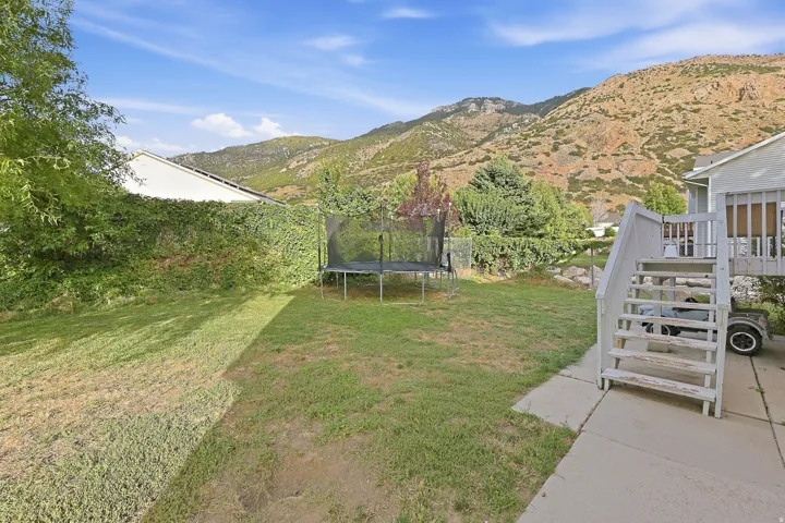 Rear yard with a lush green lawn, concrete patio, and a multi-level deck