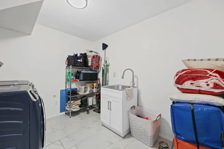 Laundry area featuring tiled flooring, a utility sink with a cabinet, and overhead lighting