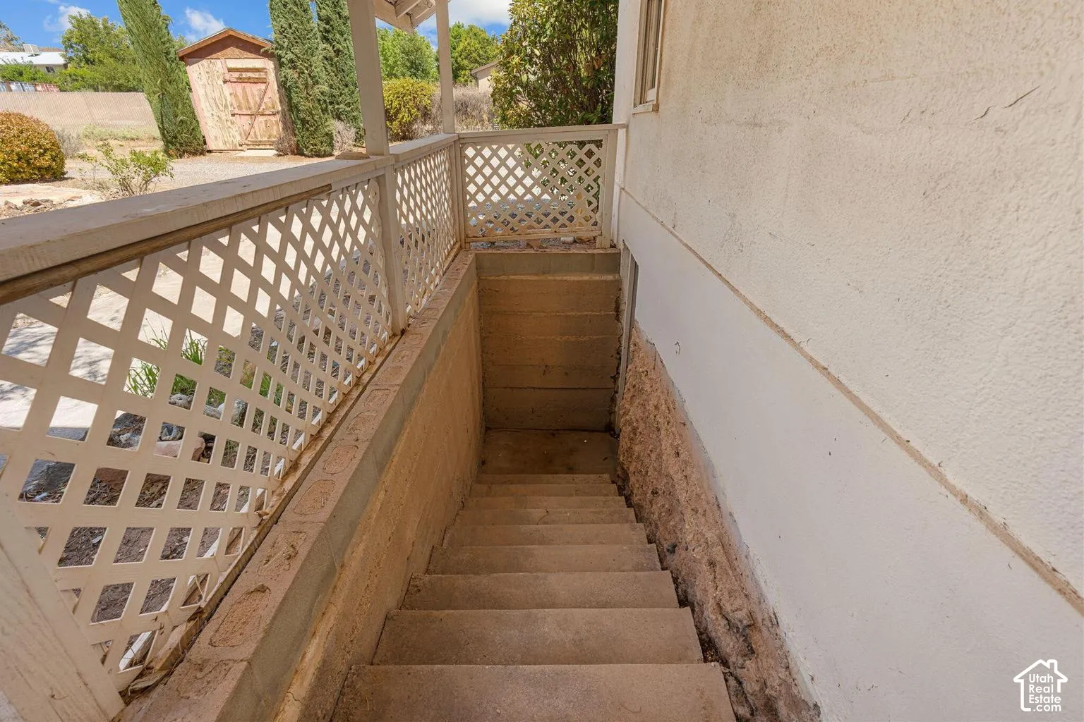 Concrete staircase with stucco-finish walls and lattice railing