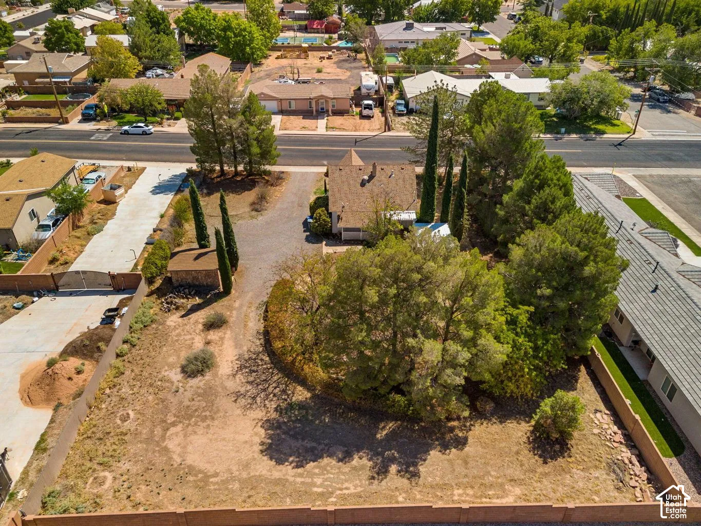 Expansive lot featuring mature trees, a long driveway, a detached structure, and perimeter fencing