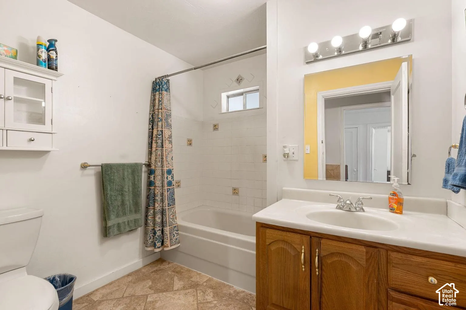White ceramic tiled shower with decorative accent tiles, a built-in bathtub, and a transom window