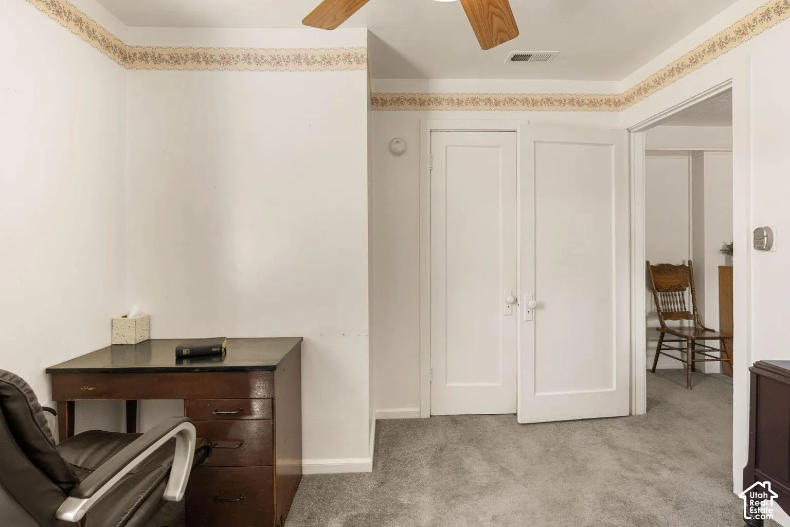 Carpeted flooring, white walls with decorative border, and a ceiling fan