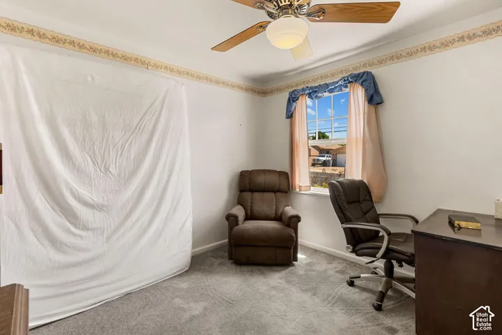 Ceiling fan with wooden blades, wall-to-wall carpeting, and a window providing natural light