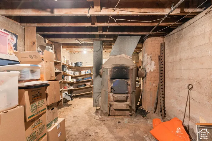Exposed ceiling joists, concrete foundation walls, and an antique furnace