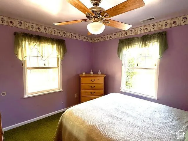 Recessed lighting with wood-finish ceiling fan, two double-hung windows, and green carpeting