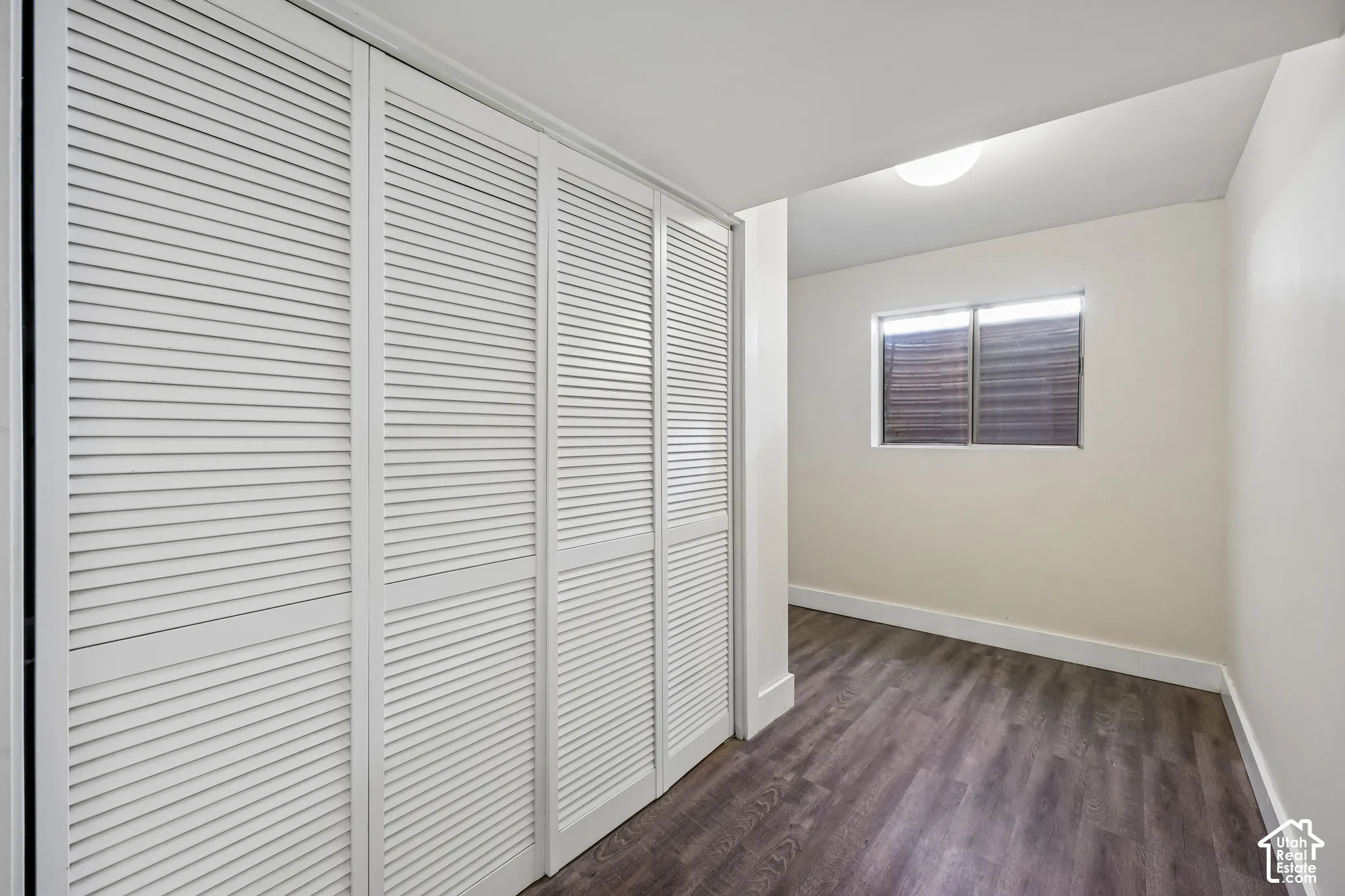Louvered closet doors, wood-finish flooring, and a flush-mount ceiling light