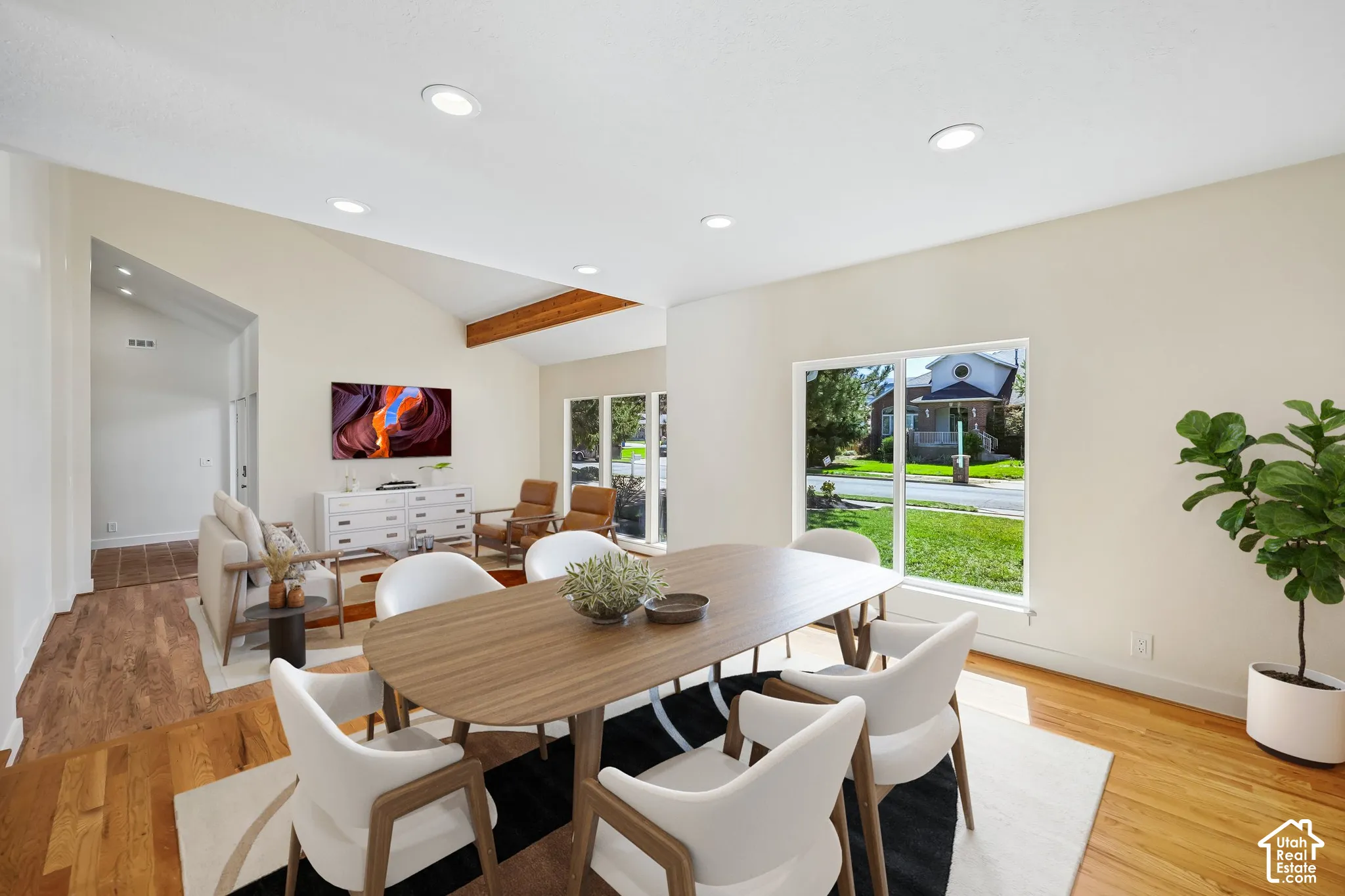 Vaulted ceilings with exposed wood beams, recessed lighting, expansive windows, and wood-finish flooring