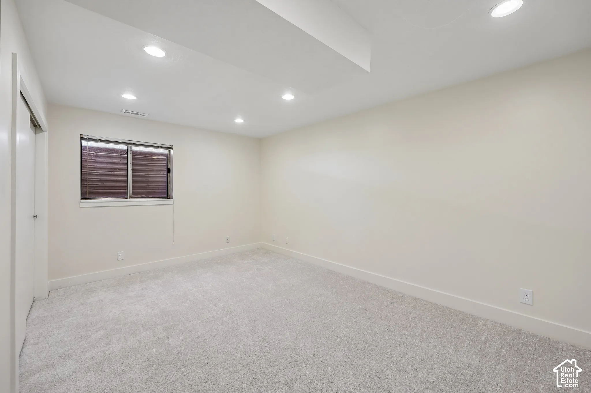 Recessed lighting illuminating the light-colored walls and grey carpeting
