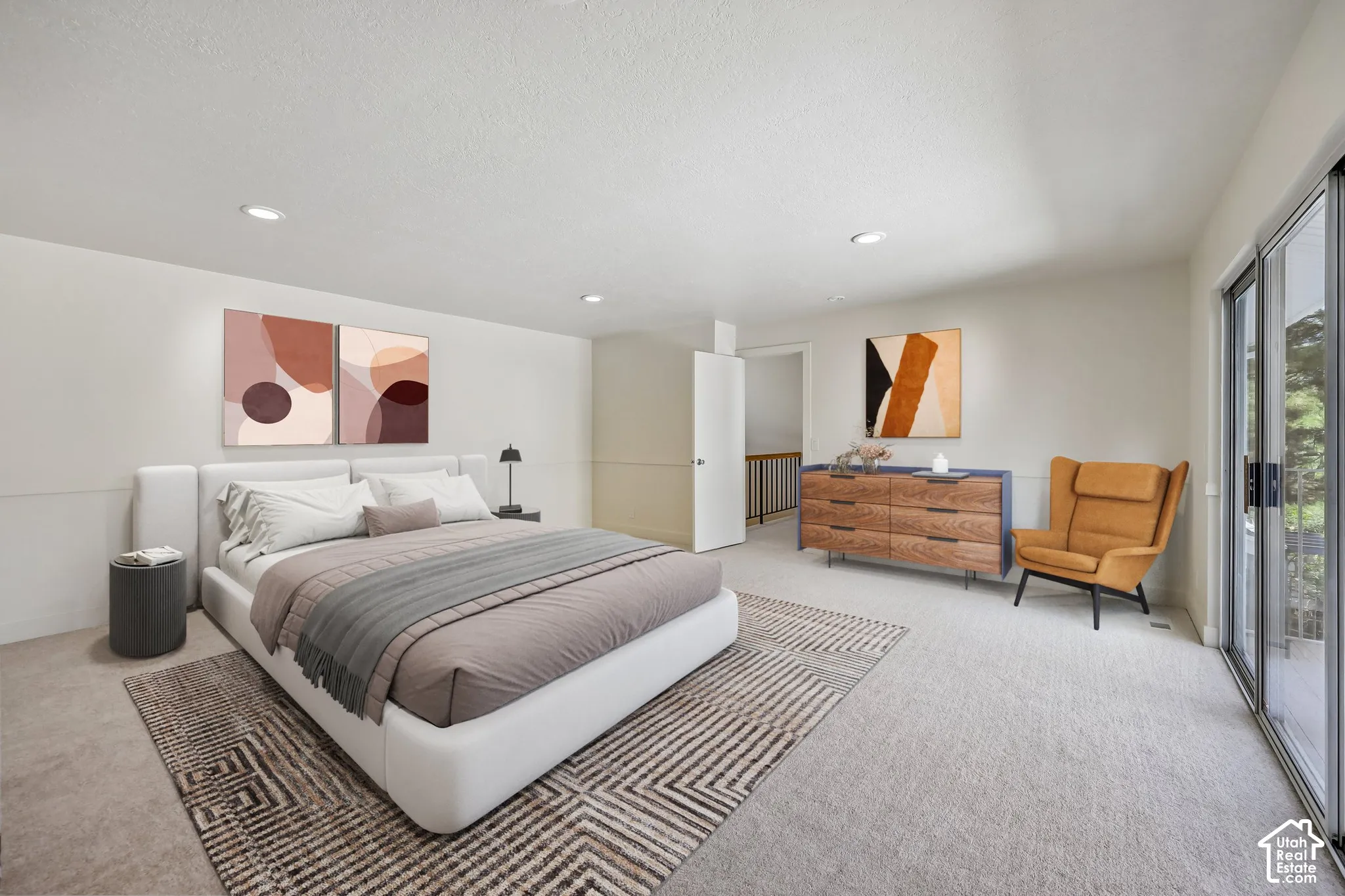 Recessed ceiling lighting, light-toned wall paneling, sliding glass door, neutral-toned carpeting, and a visible doorway to an interior space