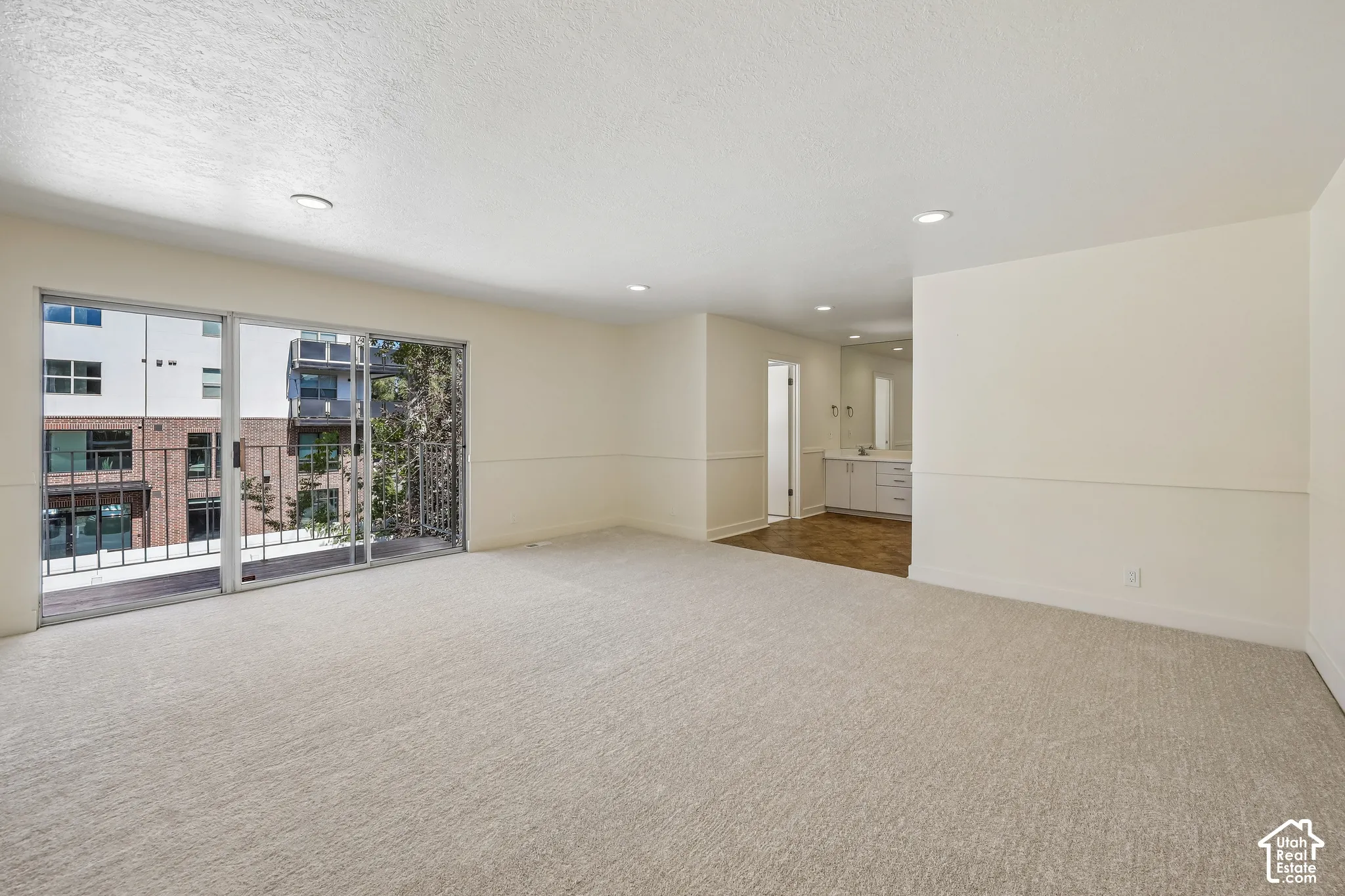 Expansive room featuring light-colored carpeting and recessed lighting
