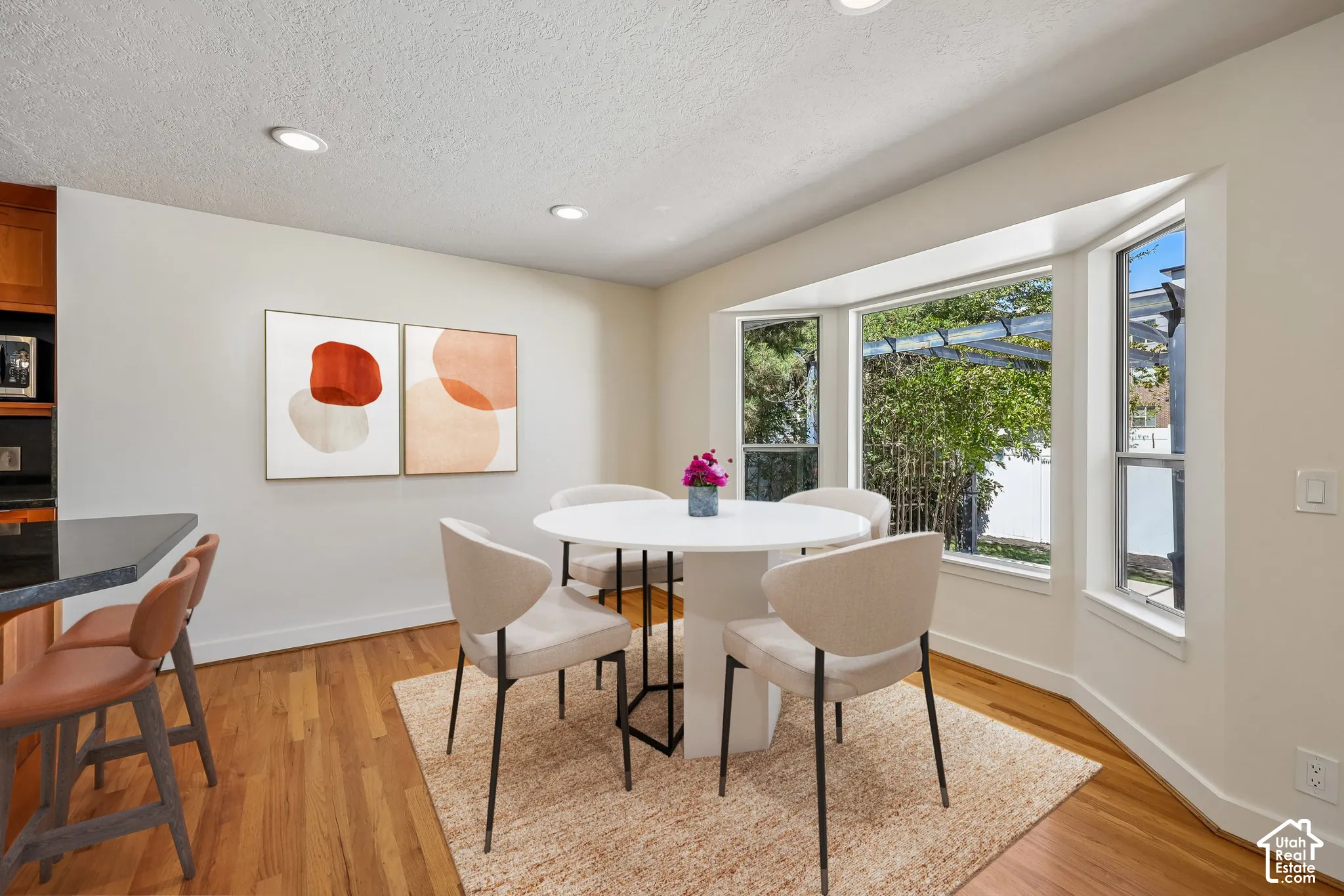Bay window with multiple panes, recessed ceiling lighting, wood-finish flooring, and a kitchen counter with an overhang