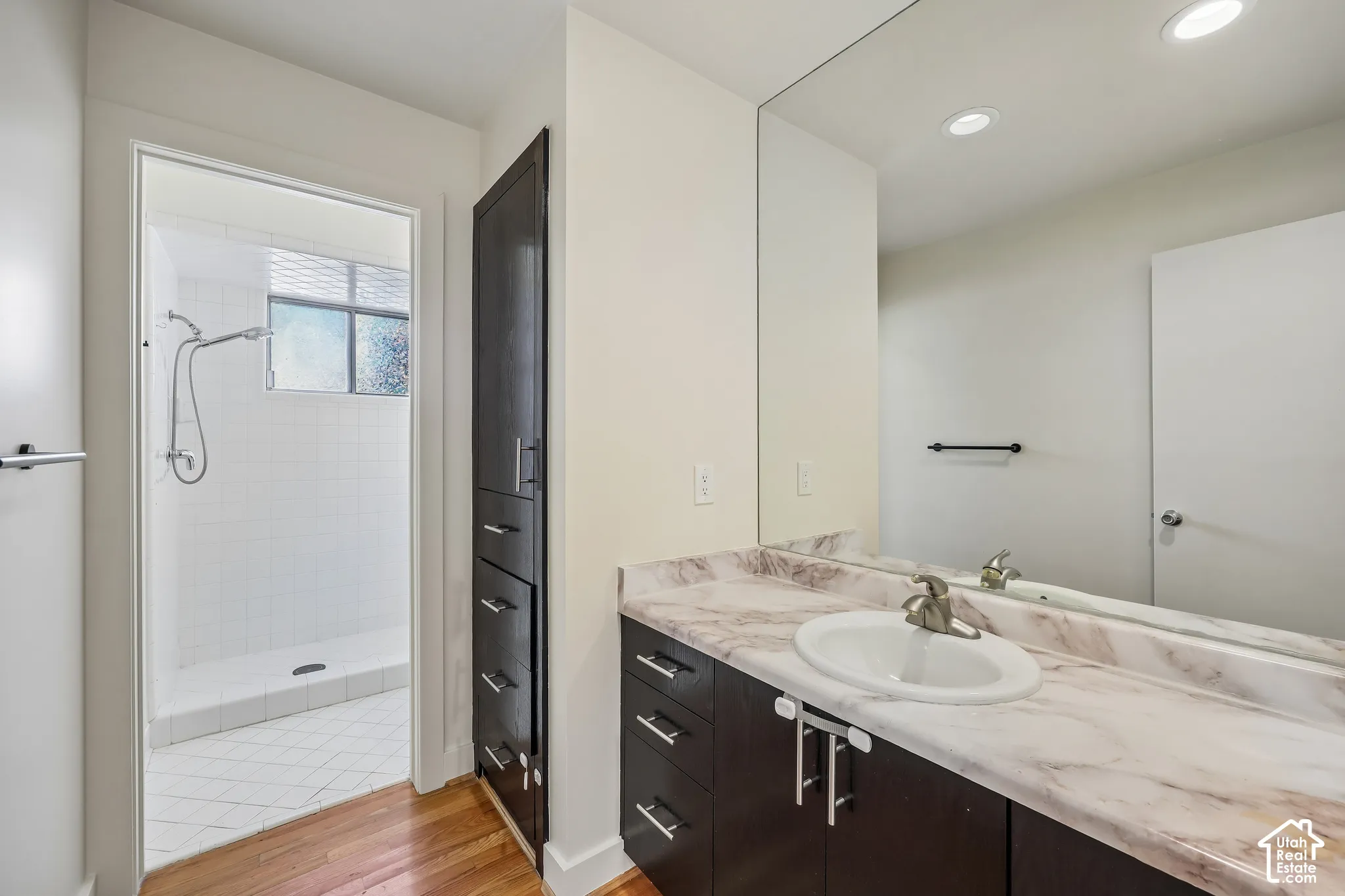 Vanity with a single basin sink, extensive countertop, and dark wood-finish cabinetry