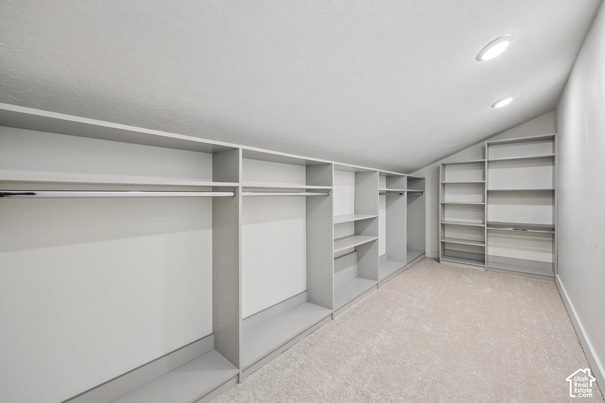 Recessed lighting illuminates the carpeted floor and built-in shelving, providing extensive storage options