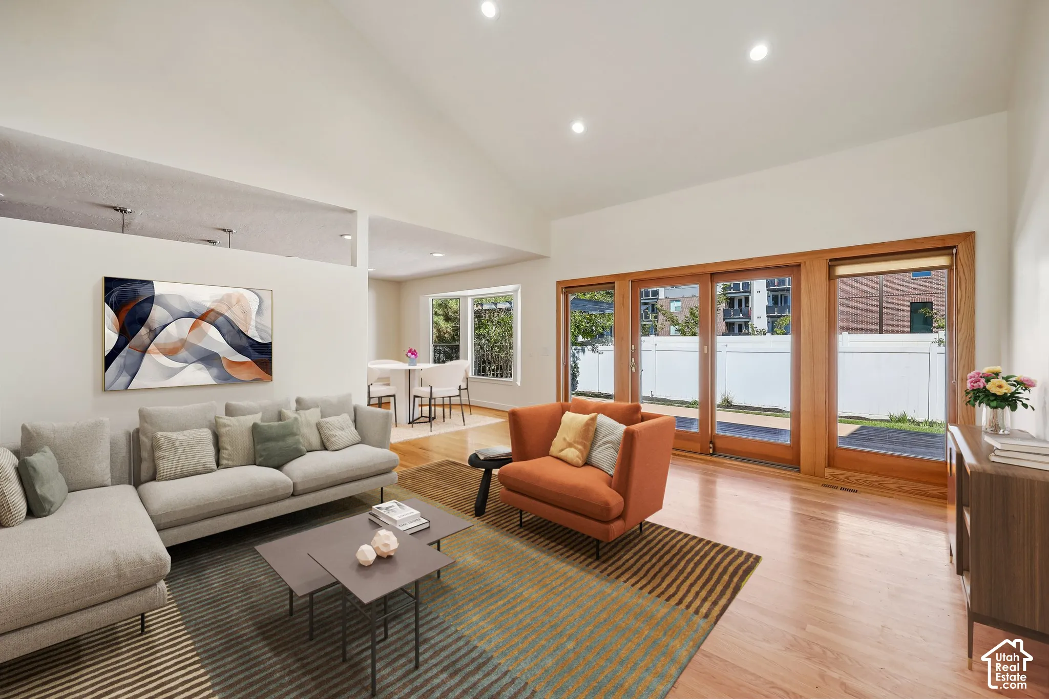 Vaulted ceiling with recessed lighting, wood-finish flooring, and large sliding glass doors providing outdoor access