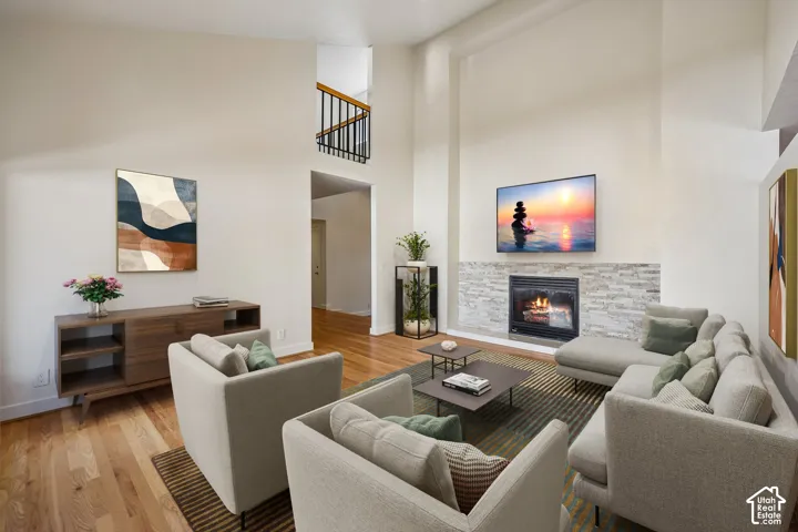 Open-concept living area featuring soaring ceilings, a two-story layout with mezzanine-level railing, and hardwood flooring throughout